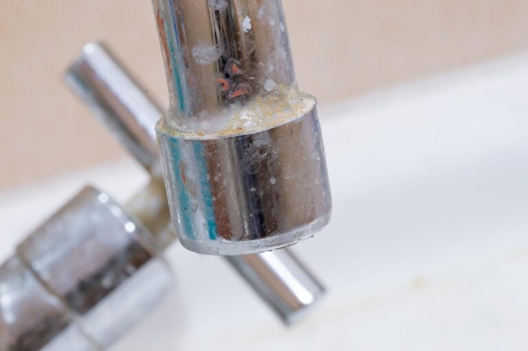 Close-up of a bathroom faucet with visible limescale and mineral deposits on the metal surface.